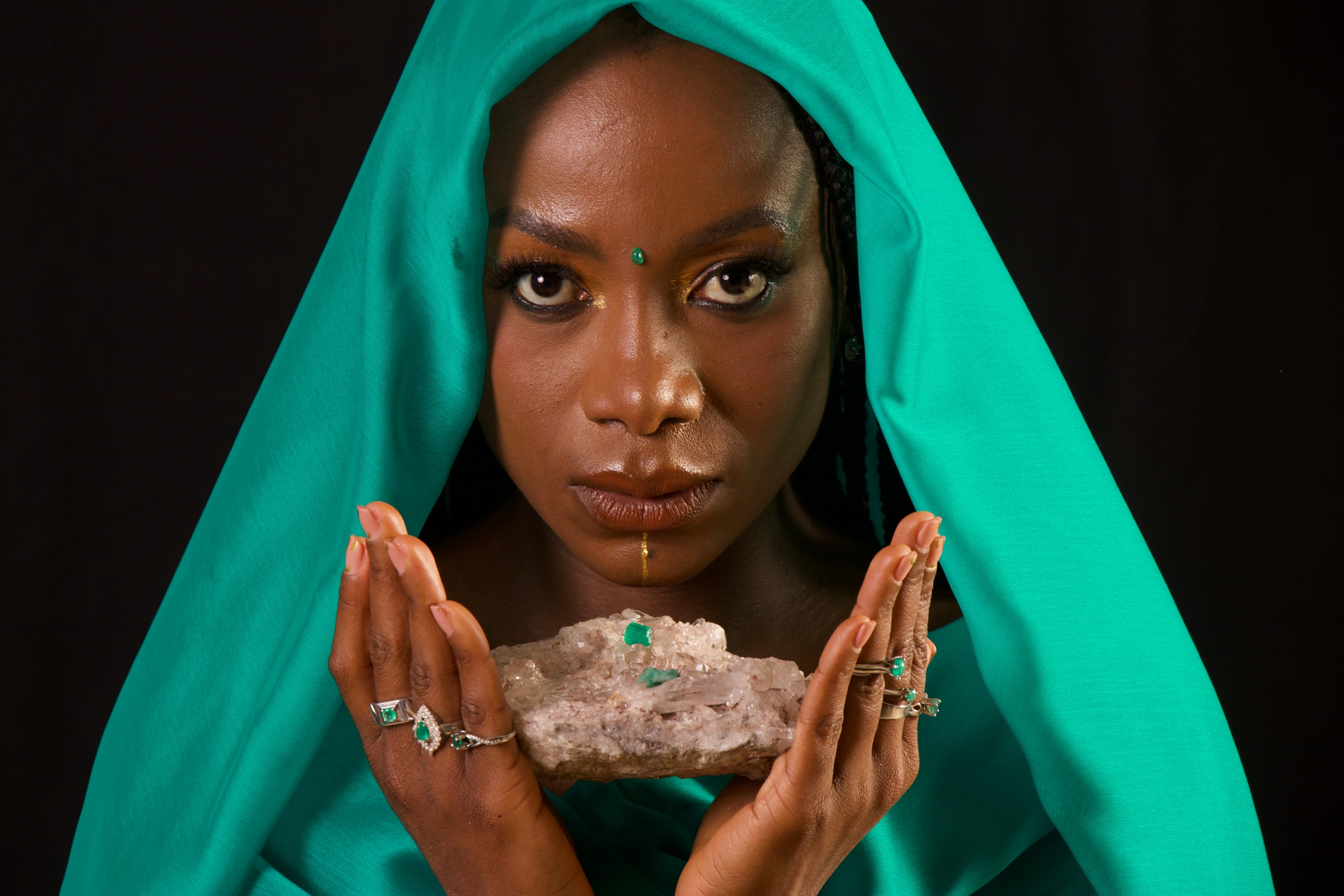 Modelo afro colombiana con turbante verde y cluster de esmeraldas